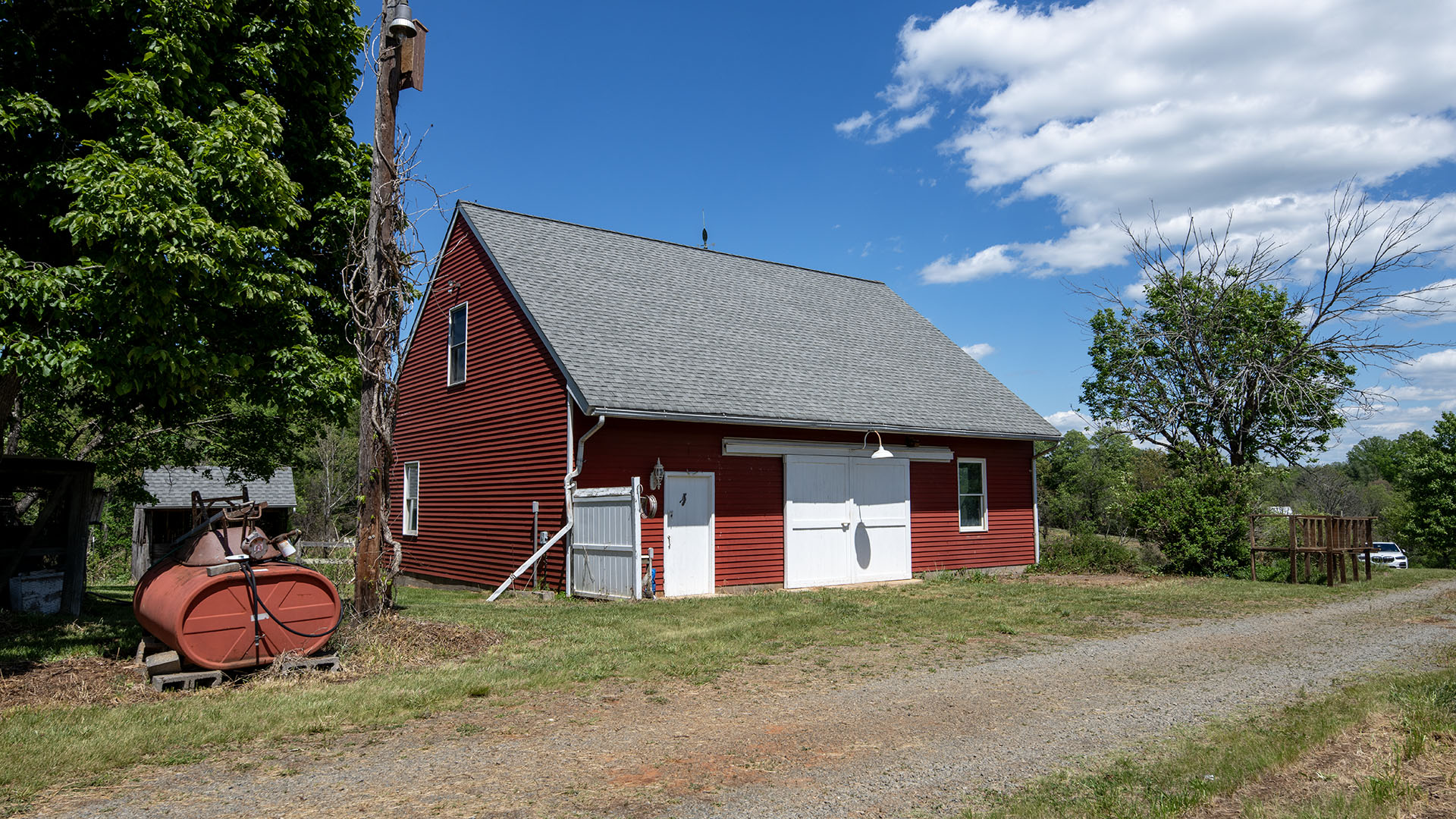 Red barn with white doors at Asgardd Farm in Afton VA with gravel drive and open countryside