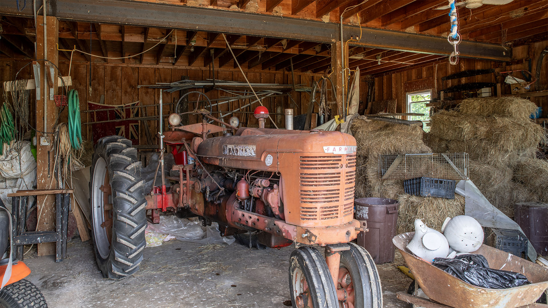 Interior of the agricultural barn at Asgardd Farm near Greenwood with vintage Farmall tractor and hay storage