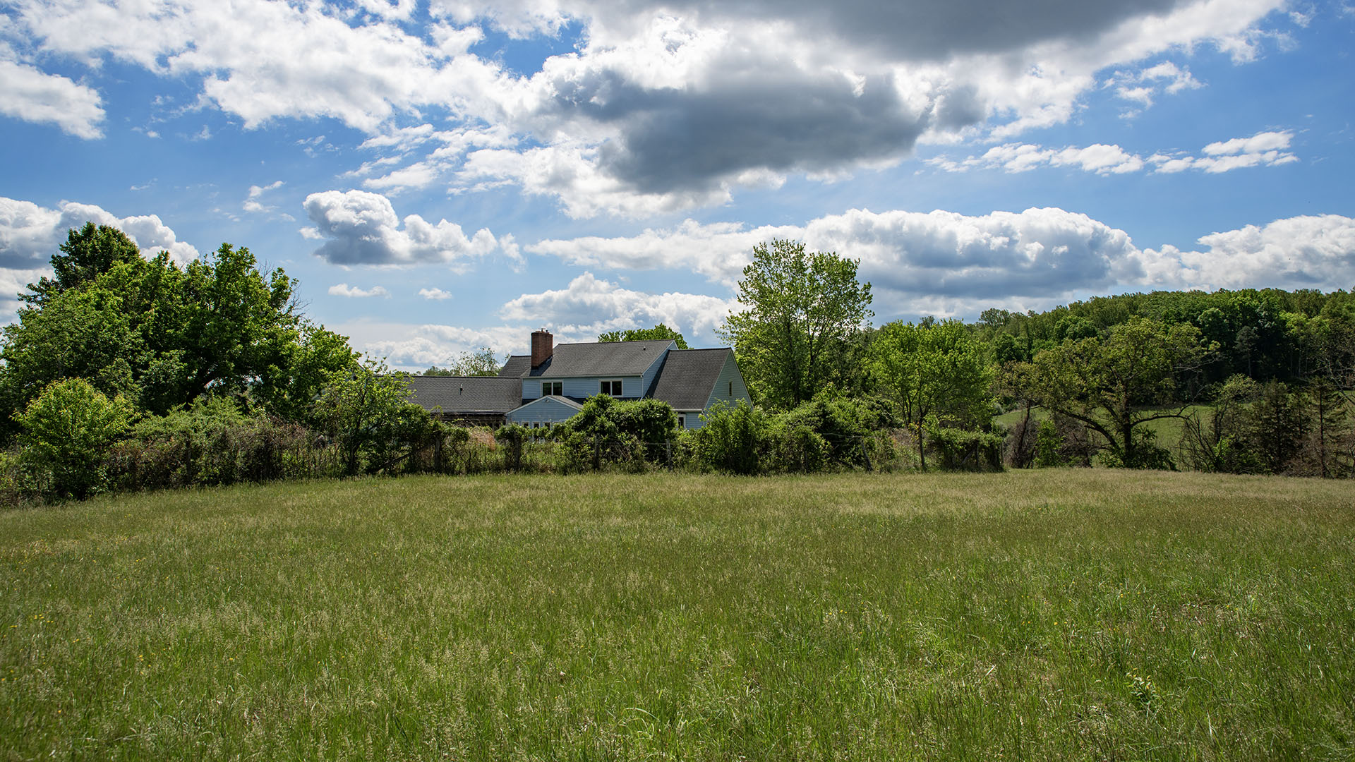 Fenced vegetable garden at Asgardd Farm in Afton VA with farmhouse in the distance and rolling countryside