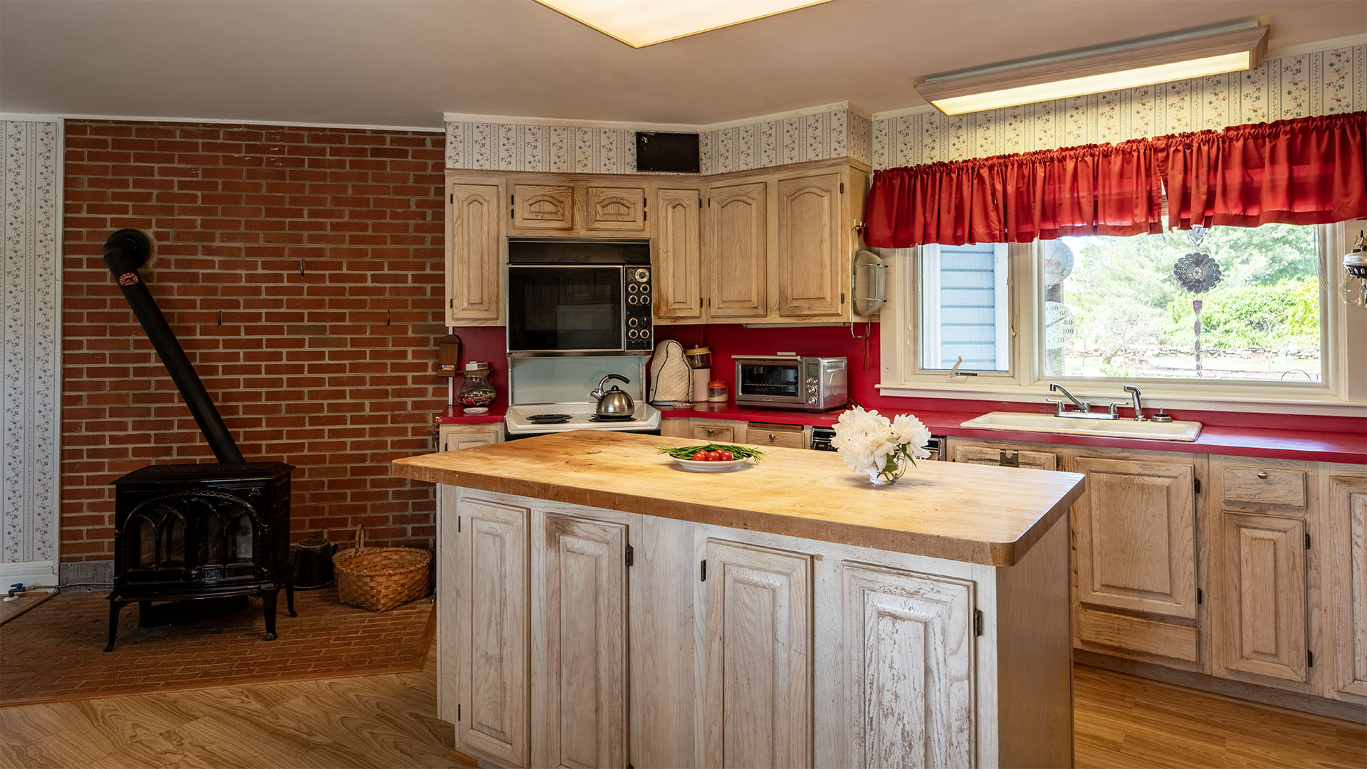 Kitchen at Asgardd Farm in Albemarle County with wood cabinets, island, brick wall and woodstove