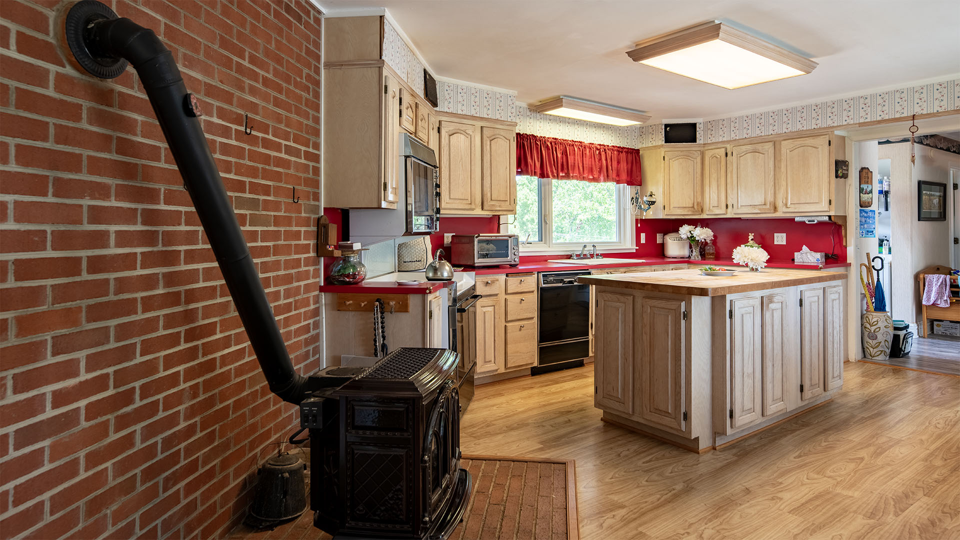 Afton VA farmhouse kitchen at Asgardd Farm with woodstove, brick wall, center island and warm country style
