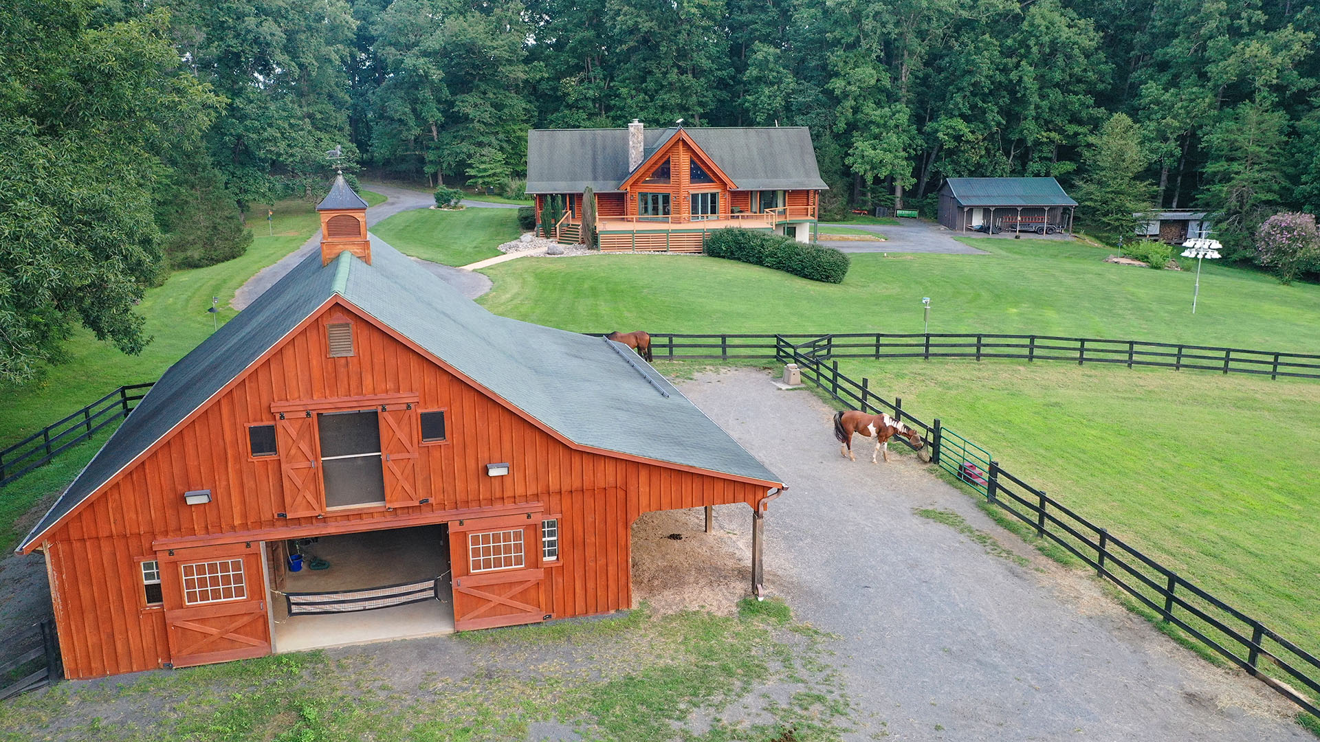 Aerial view of 3638 Oak Park Road horse farm showing the log home, stable, fenced pastures and surrounding acreage in Madison Virginia