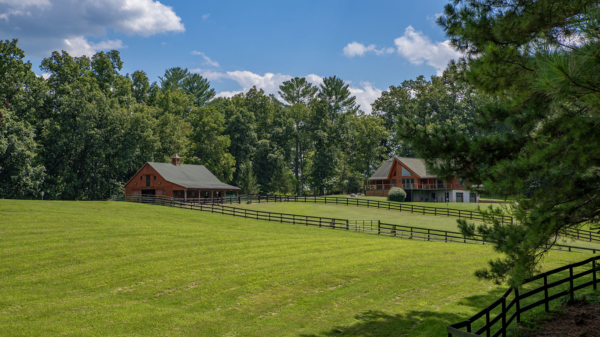 Aerial view of 3638 Oak Park Road showing the horse stable, fenced pastures, horses and log home on 44 acres in Madison Virginia